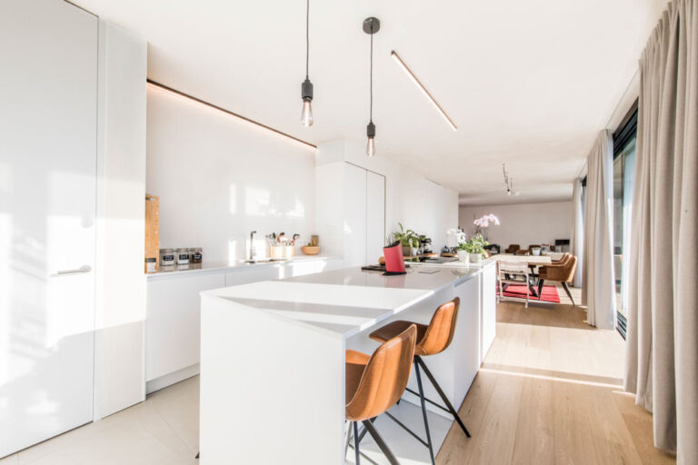 Witte open keuken met bruine stoelen